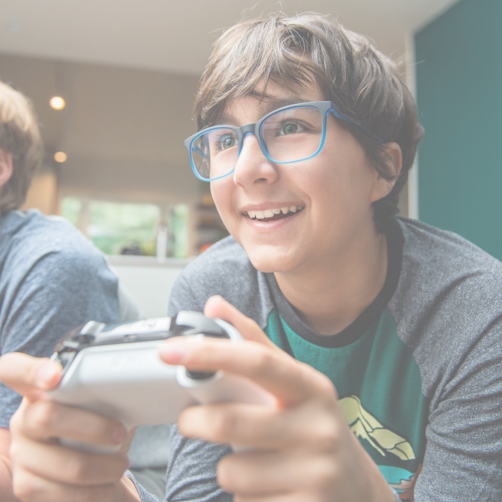Two teenagers are wearing green round and blue square Blokz blue light glasses to protect their eyes from gaming.