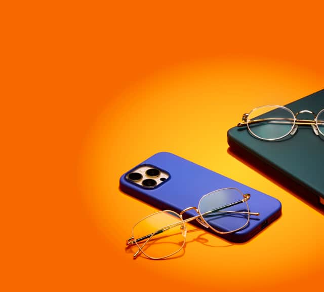 Gold-framed blue light glasses on a blue phone against an orange background, with labels highlighting their features: blue light filtering, UV protection, anti-scratch, and anti-reflective.