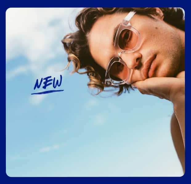 Chase Stokes wears Zenni frames with EyeQLenz featuring Zenni ID Guard lenses, posing outdoors under a bright sky
