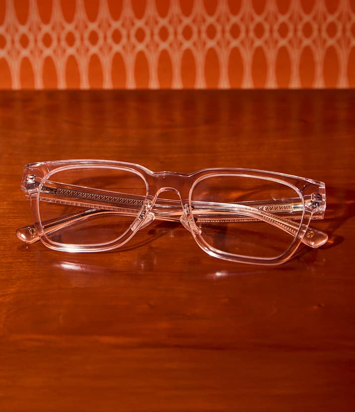 Clear square Zenni eyeglass frames displayed on a polished wood surface.