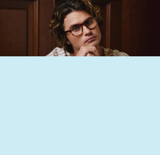 Chase Stokes wears square tortoiseshell Zenni frames against a dark brown background.