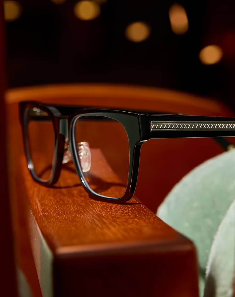 Black square Zenni glasses with clear temple tips on a wood surface.