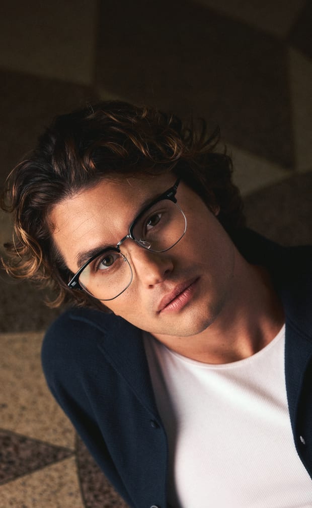 Black browline Zenni glasses worn by Chase Stokes, indoors.