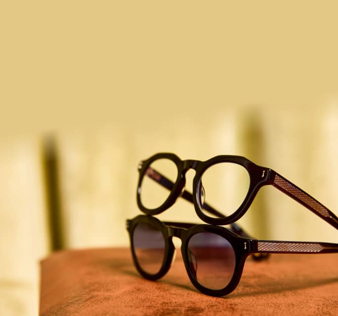 Black round Zenni glasses stacked on matching brown gradient Zenni sunglasses, on a wood surface.