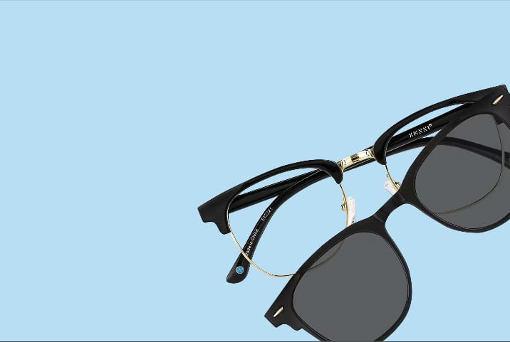 A black browline frame with dark clip-on lenses pops against a clean sky-blue backdrop.