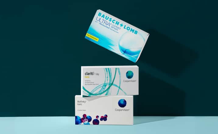 An assortment of three contact lens boxes stacked in a dynamic arrangement against a dark teal background.