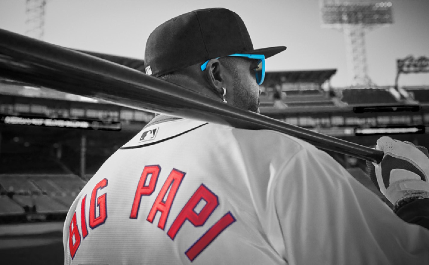 Image of David Ortiz in black and white, wearing Zenni sunglasses and a jersey that says ‘Big Papi’ on the back, carrying a baseball bat.