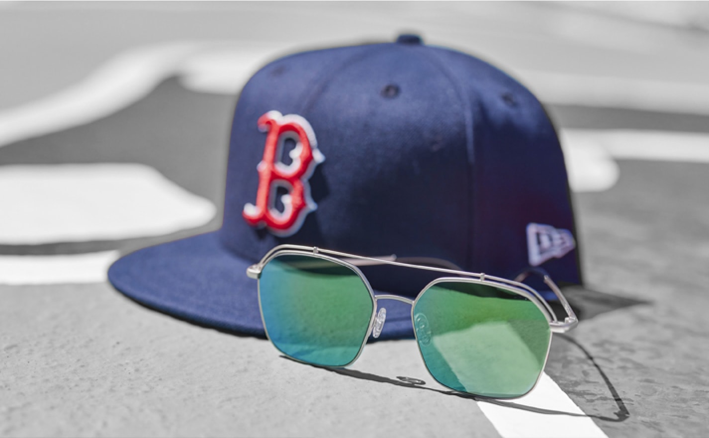 Image of a Boston Red Sox hat resting on a baseball base, with a pair of Zenni glasses in front of it.