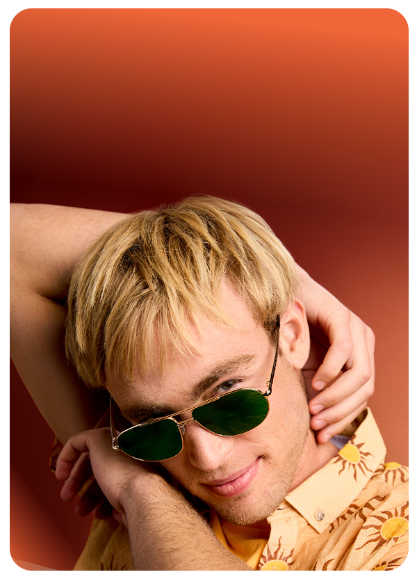 Man in green-tinted lens Zenni aviator sunglasses, striking a confident pose in a yellow shirt.