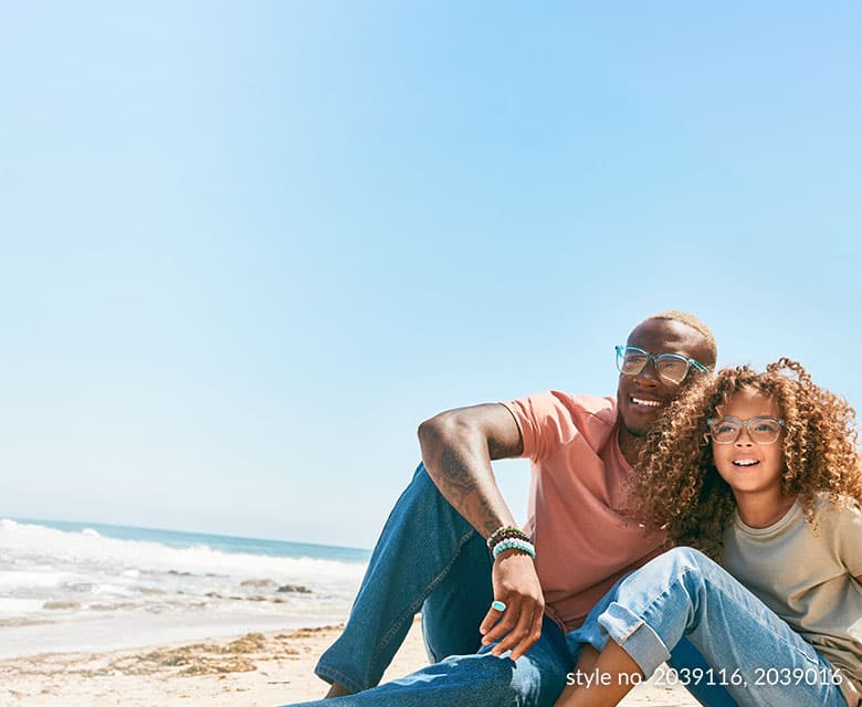 A father and daughter on the beach wearing recycled plastic glasses frames.