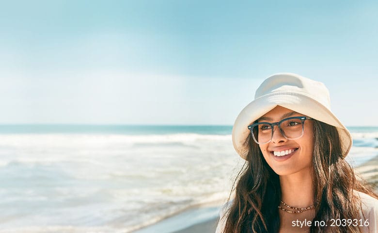 A woman at the beach wearing a sunhat and square recycled plastic glasses frames.