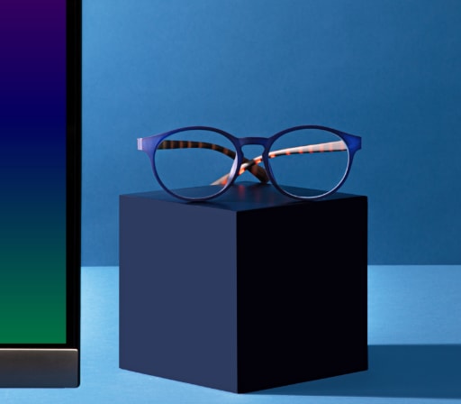 Image of a pair of Zenni glasses placed on a blue cube, against a blue background.