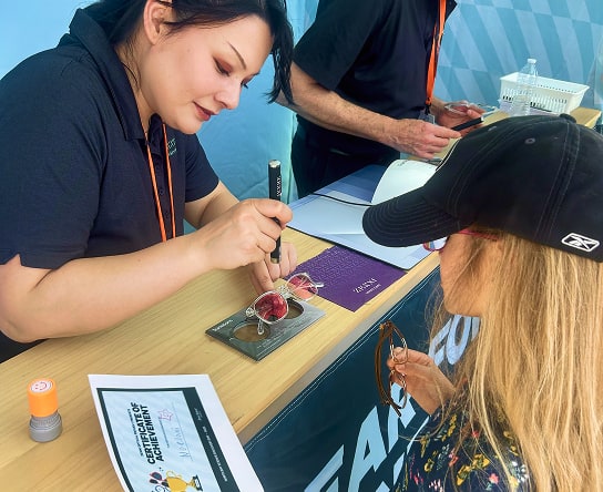 A Zenni Team member demonstrating the IR light reflecting capabilities of a Zenni lens, inside the Zenni event booth.