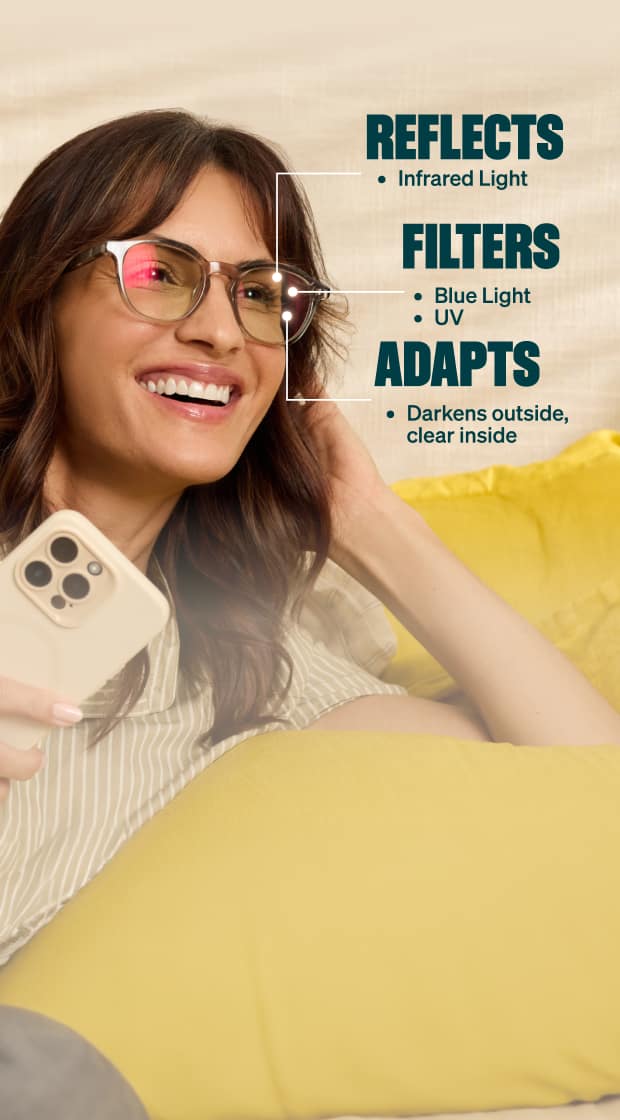 A woman wearing glasses reclines on a bed, smiling while holding a smartphone. Text on the image highlights the lenses’ features: they reflect infrared light, filter blue light and UV, and adapt by darkening outside while remaining clear indoors.