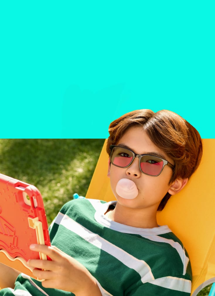 Boy lounging outside in striped shirt and pink-sheen EyeQLenz with Zenni ID Guard glasses, blowing bubble gum.