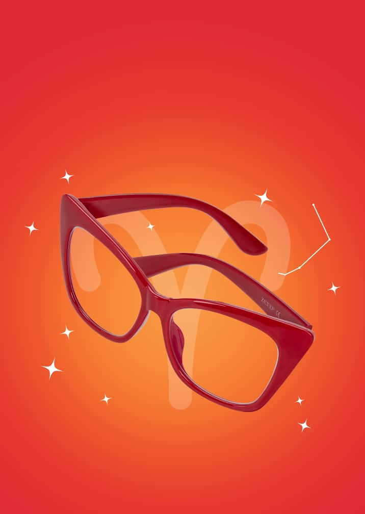 Red oversized cat-eye glasses on an orange zodiac background with the Aries symbol and constellation.