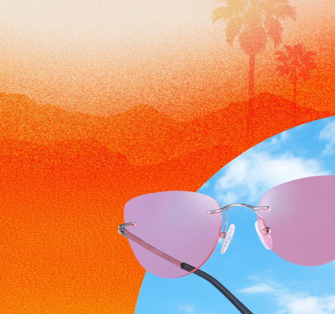 Cat-eye rimless Zenni sunglasses with pink lenses on a blue sky and hazy orange desert landscape.