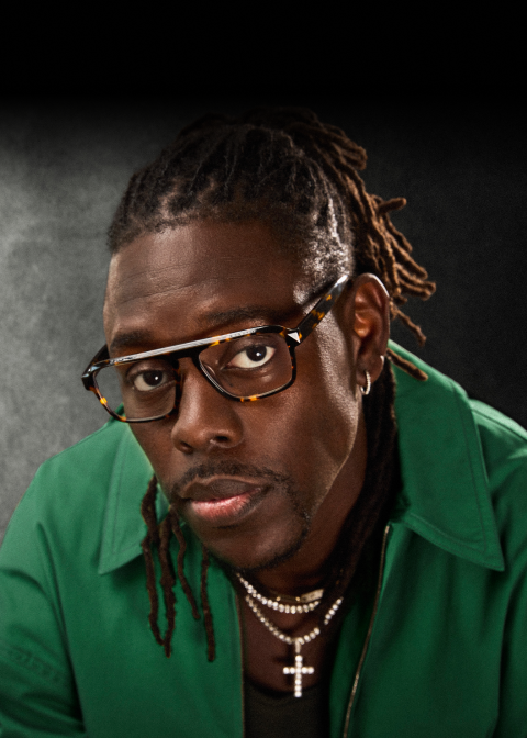 Boston Celtics point guard Jrue Holiday wears optical glasses “Dynamo” from his collection with Zenni, styled with a green jacket, jewelry and his hair slicked back.