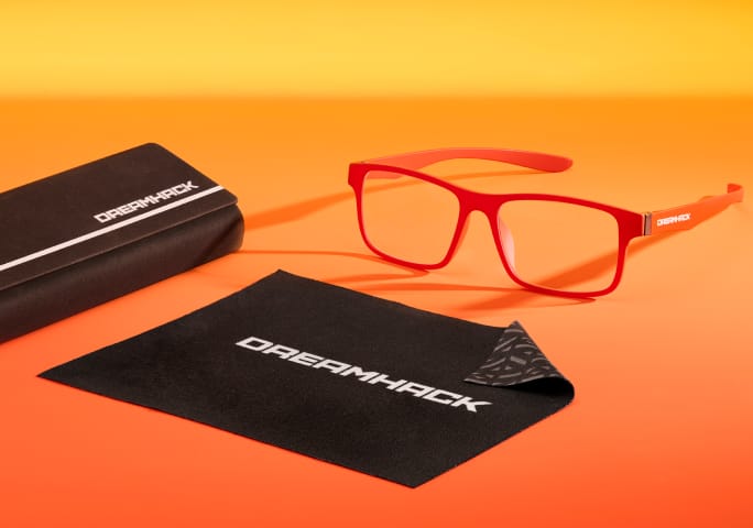DreamHack branded Zenni eyewear set with dark orange glasses, black case, and cleaning cloth on orange background.