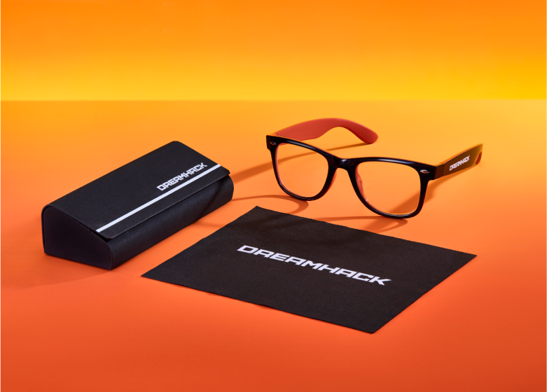 Black computer glasses with red arms, accompanied by a closed black case and cleaning cloth, on an orange background