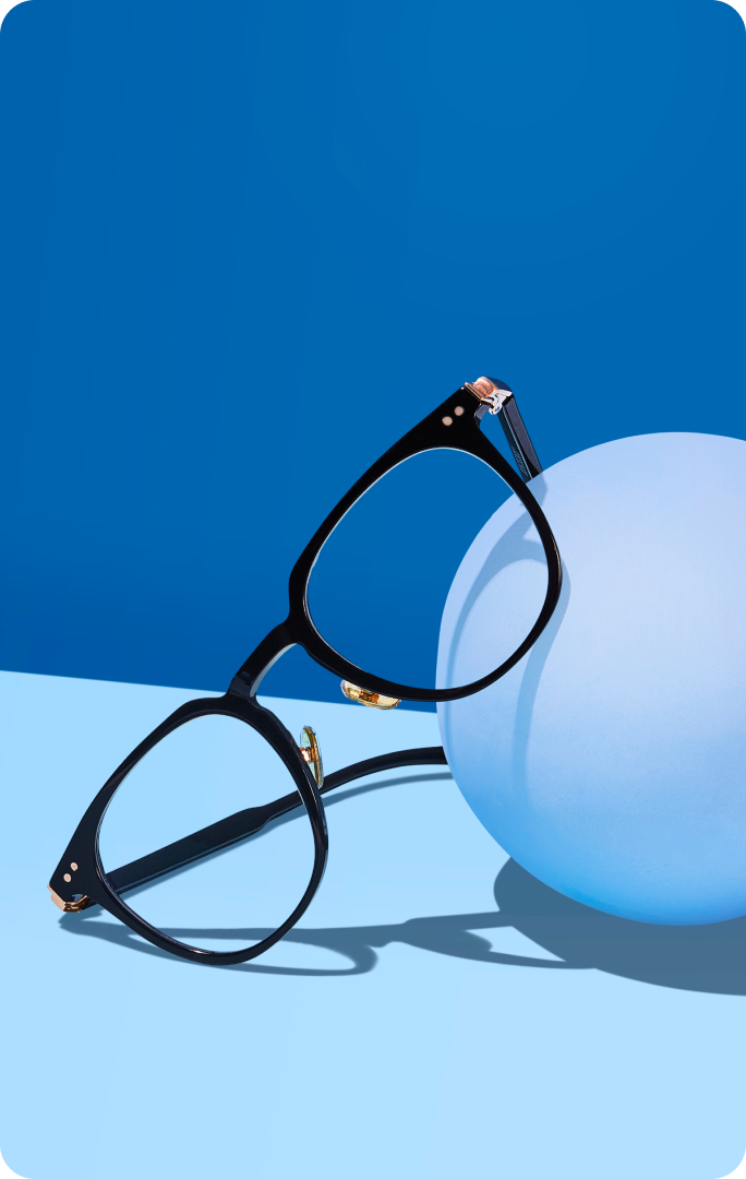 Black eyeglasses in front of a blue background, next to a blue sphere. Text reads “Blokz®. A clear lens that filters 16x more blue light than standard lenses” with a “Shop now” button.