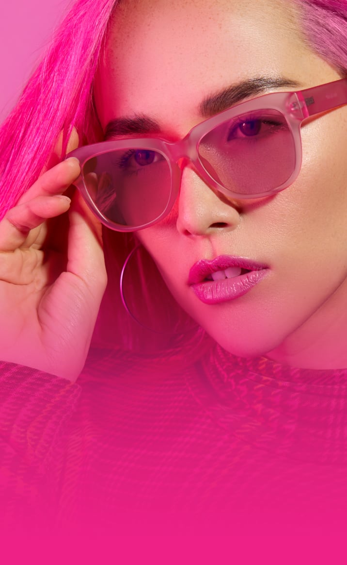 Woman with pink hair wearing pink plastic frames with rose tinted lenses.