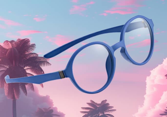 Blue Zenni Optiflex eyeglass frames floating against a pink sunset sky with palm tree silhouettes.