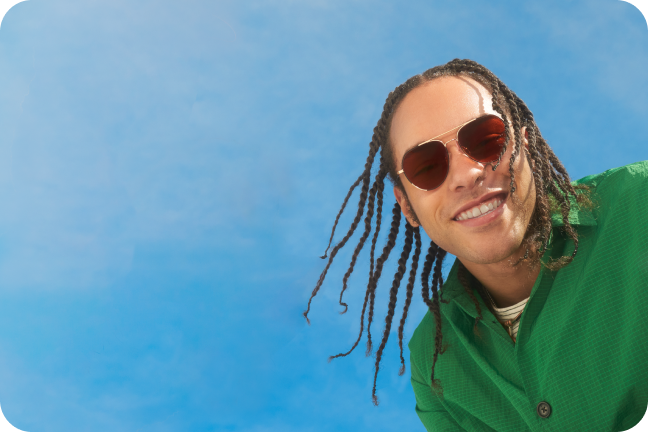 A mean with braids wearing custom metal aviator sunglasses with brown lenses.