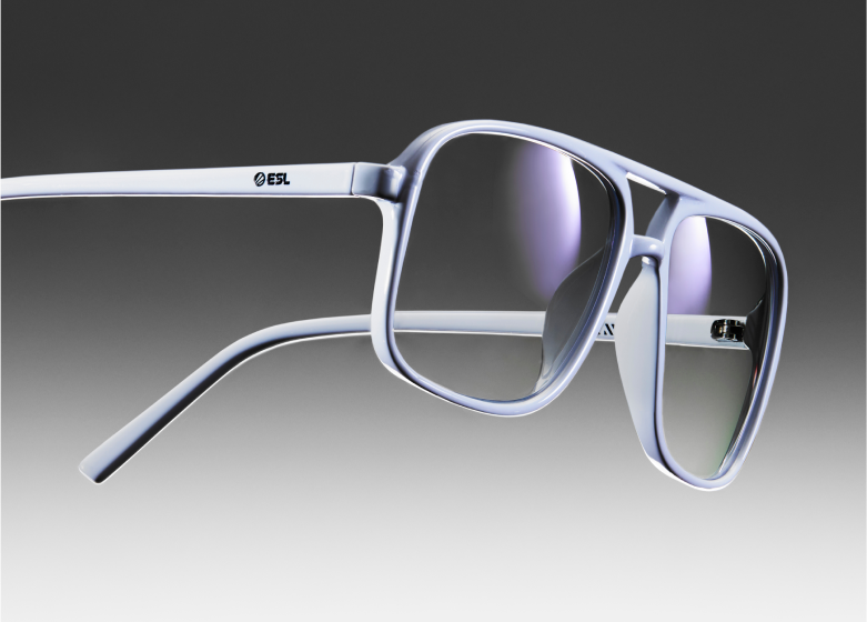 Close-up of a sleek pair of Zenni glasses with a futuristic, silver metallic frame against a gradient gray background.