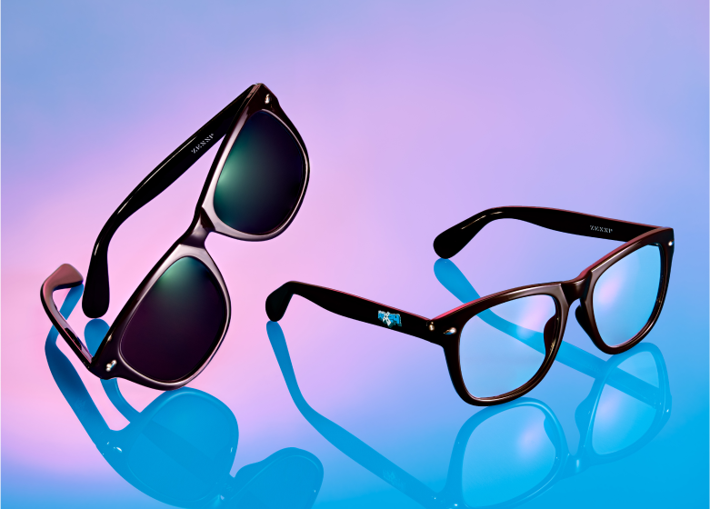 Two pairs of Zenni glasses, one with sunglasses lenses and the other with clear lenses, displayed on a reflective surface with a blue and purple gradient backdrop.