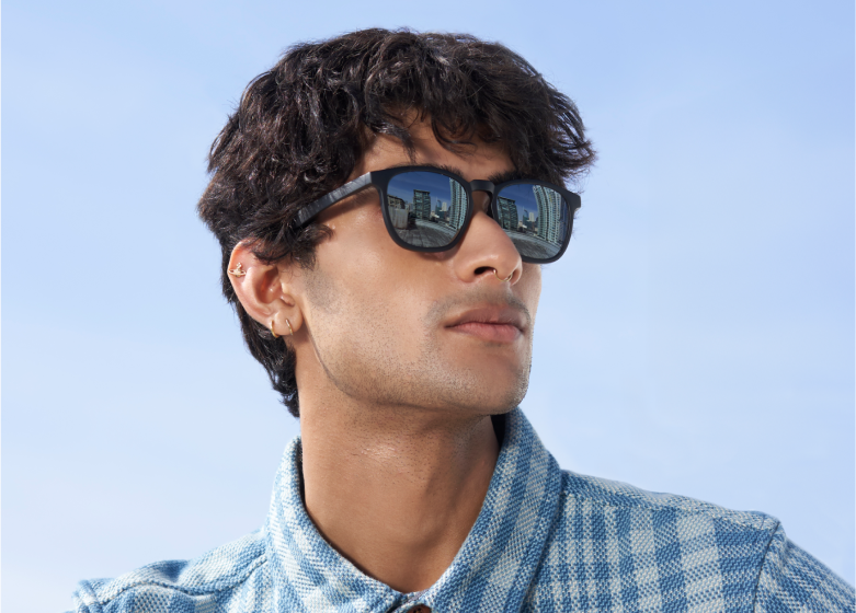 Man wearing Zenni sunglasses outdoors, reflecting the sky in his lenses, against a clear blue background.