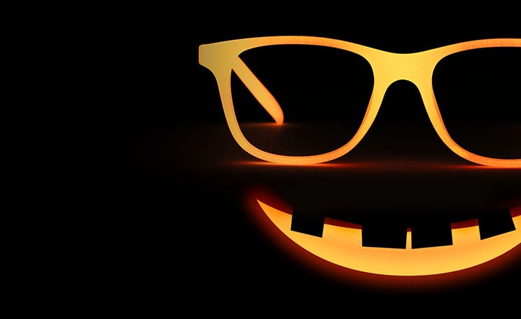 Image of Zenni kids’ glow-in-the-dark square glasses #8110619, glowing orange in the dark, above a smiling expression like a jack-o-lantern.