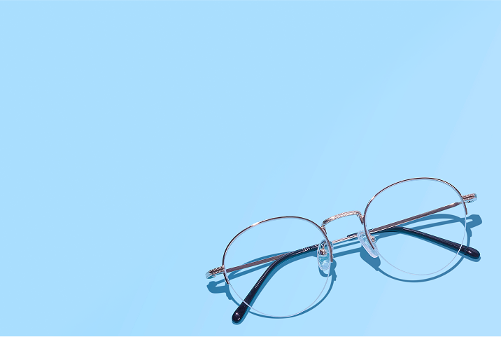 Gold halfrim glasses on a light blue background.