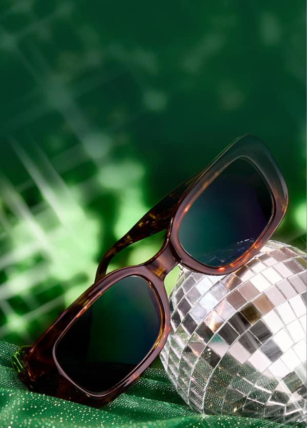 Zenni tortoiseshell square sunglasses on festive green background with small disco ball