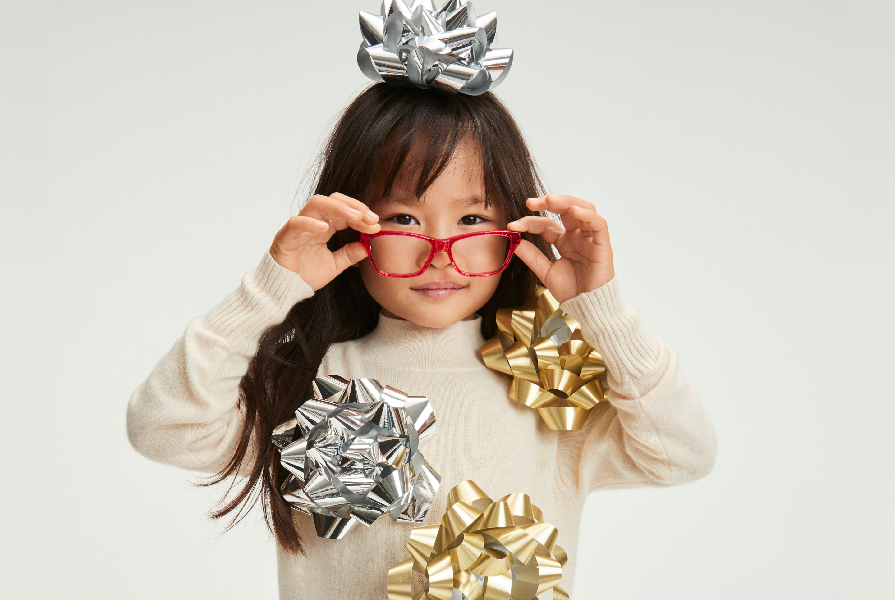 Image of a kid wearing Zenni red glasses with gift decorations on them.
