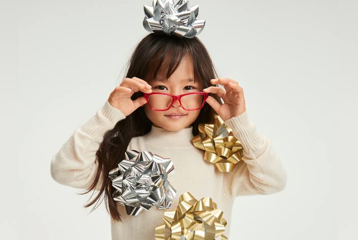 Image of a kid wearing Zenni red glasses with gift decorations on them.