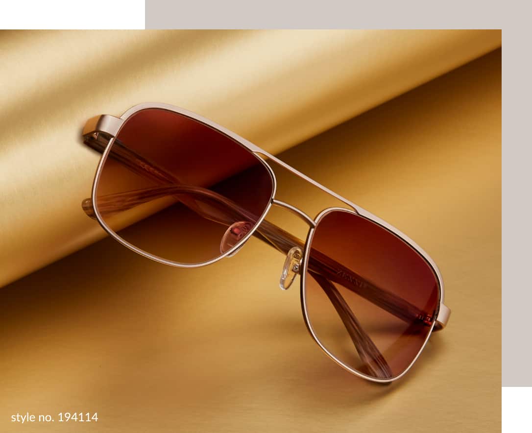 Image of a pair of Zenni premium aviator sunglasses #194114, resting against a roll of gold wrapping paper on a gold background