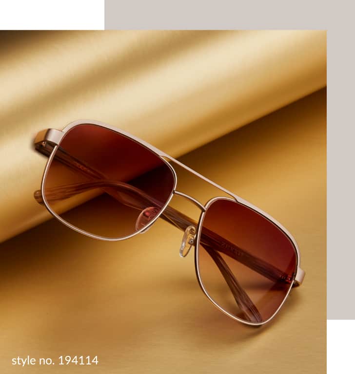 Image of a pair of Zenni premium aviator sunglasses #194114, resting against a roll of gold wrapping paper on a gold background.