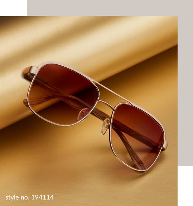 Image of a pair of Zenni premium aviator sunglasses #194114, resting against a roll of gold wrapping paper on a gold background