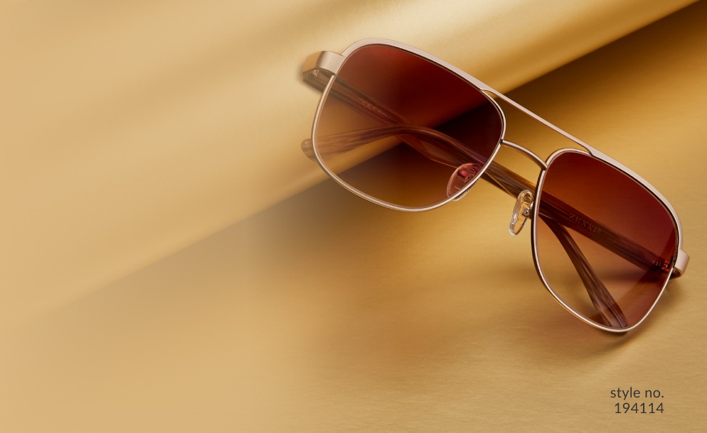 Image of a pair of Zenni premium aviator sunglasses #194114, resting against a roll of gold wrapping paper on a gold background.