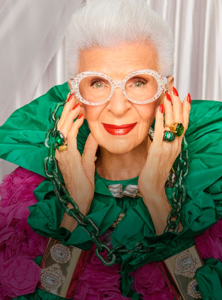 Iris Apfel wearing bold, oversized Zenni glasses with a vibrant green outfit.