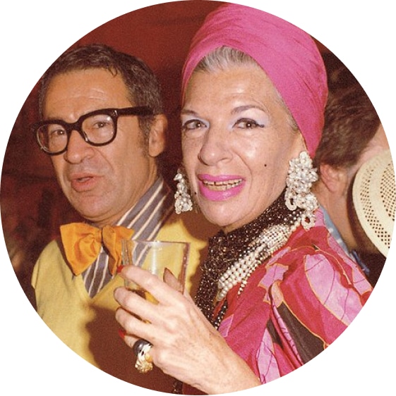 Image of Iris Apfel wearing a bright pink turban with her husband Carl. 