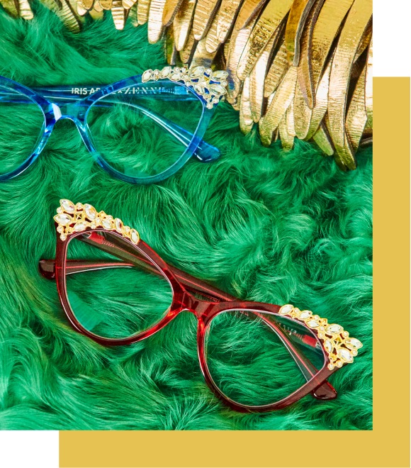 Image of two pairs of iris x Zenni tinseltown pussycat cat-eye glasses, surrounded by gold leather cut-out feathers, on a green faux-fur background.