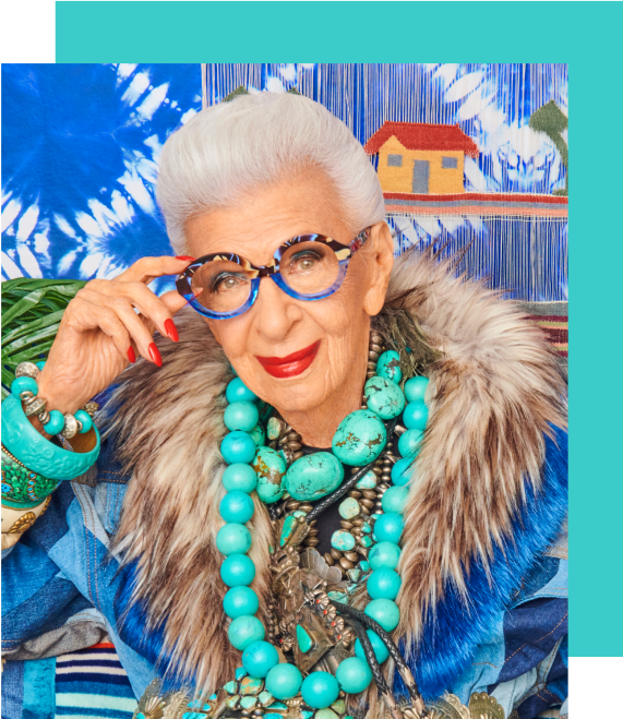 Image of Iris Apfel wearing Zenni half & half round glasses #4453239. She is nodding to the camera and is standing in front of bright blue artwork on a wall.