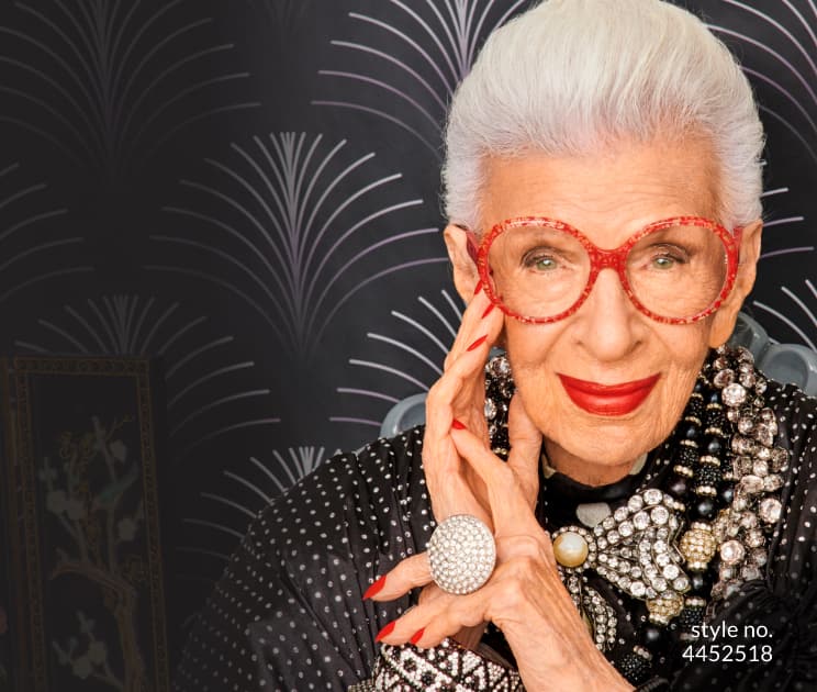 Image of Iris Apfel wearing Iris x Zenni red round glasses #4452518 against a black patterned background.