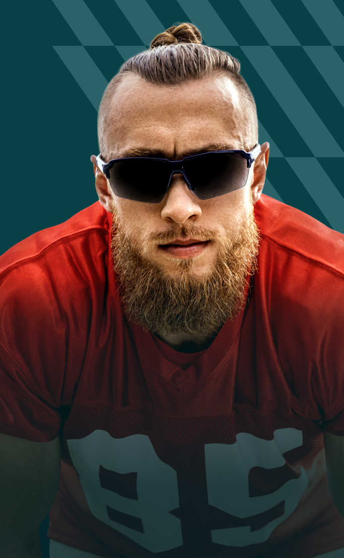 George Kittle wearing black sports sunglasses and a red athletic shirt, posing against a teal background with angular graphic patterns.