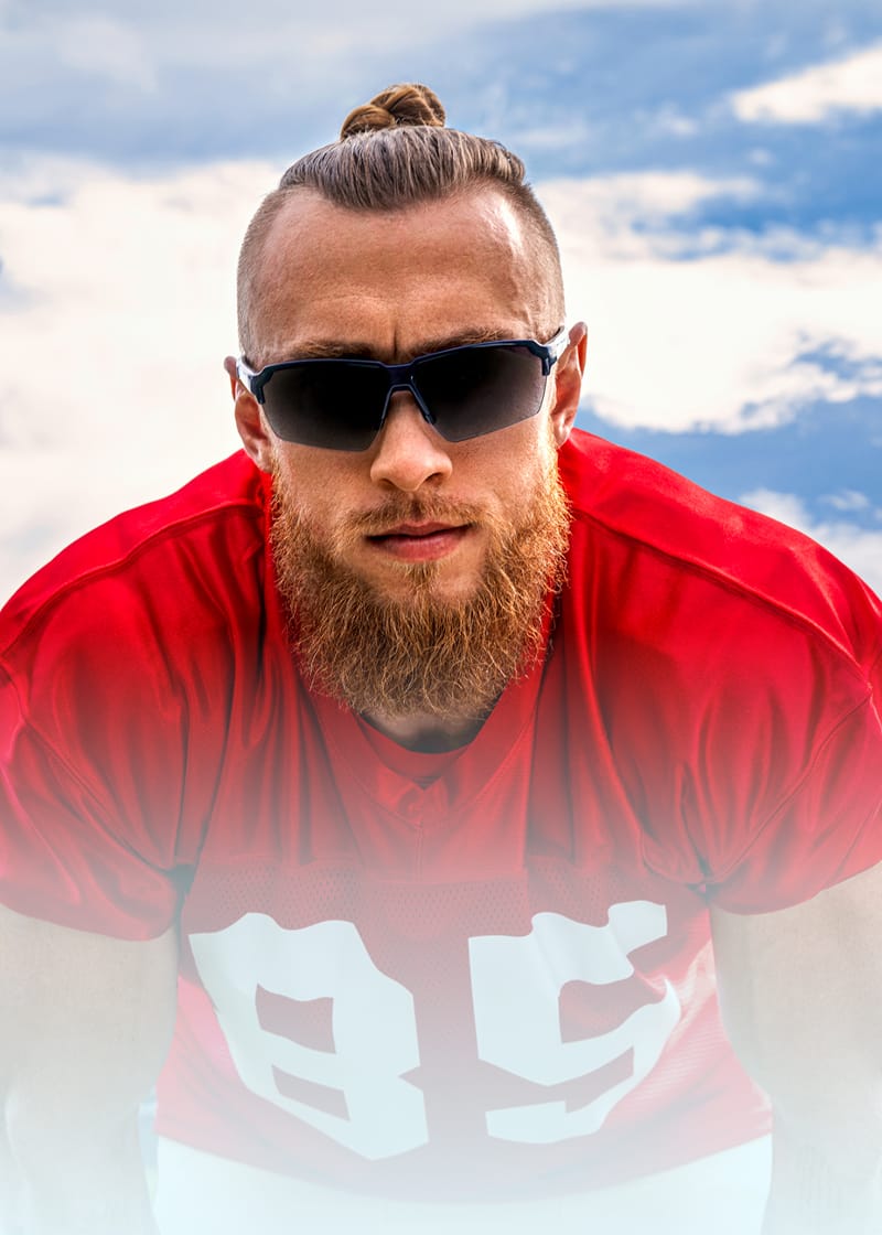 George Kittle wearing black sunglasses and a red jersey on a football field.