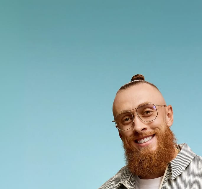 Metal-framed Zenni Kittles Collection glasses worn by George Kittle against a teal background.
