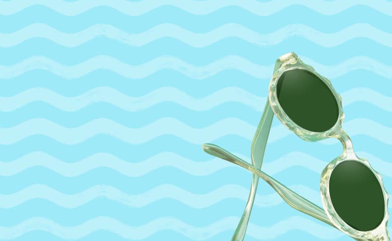 A pair of translucent green round sunglasses is shown against a wavy light blue background.