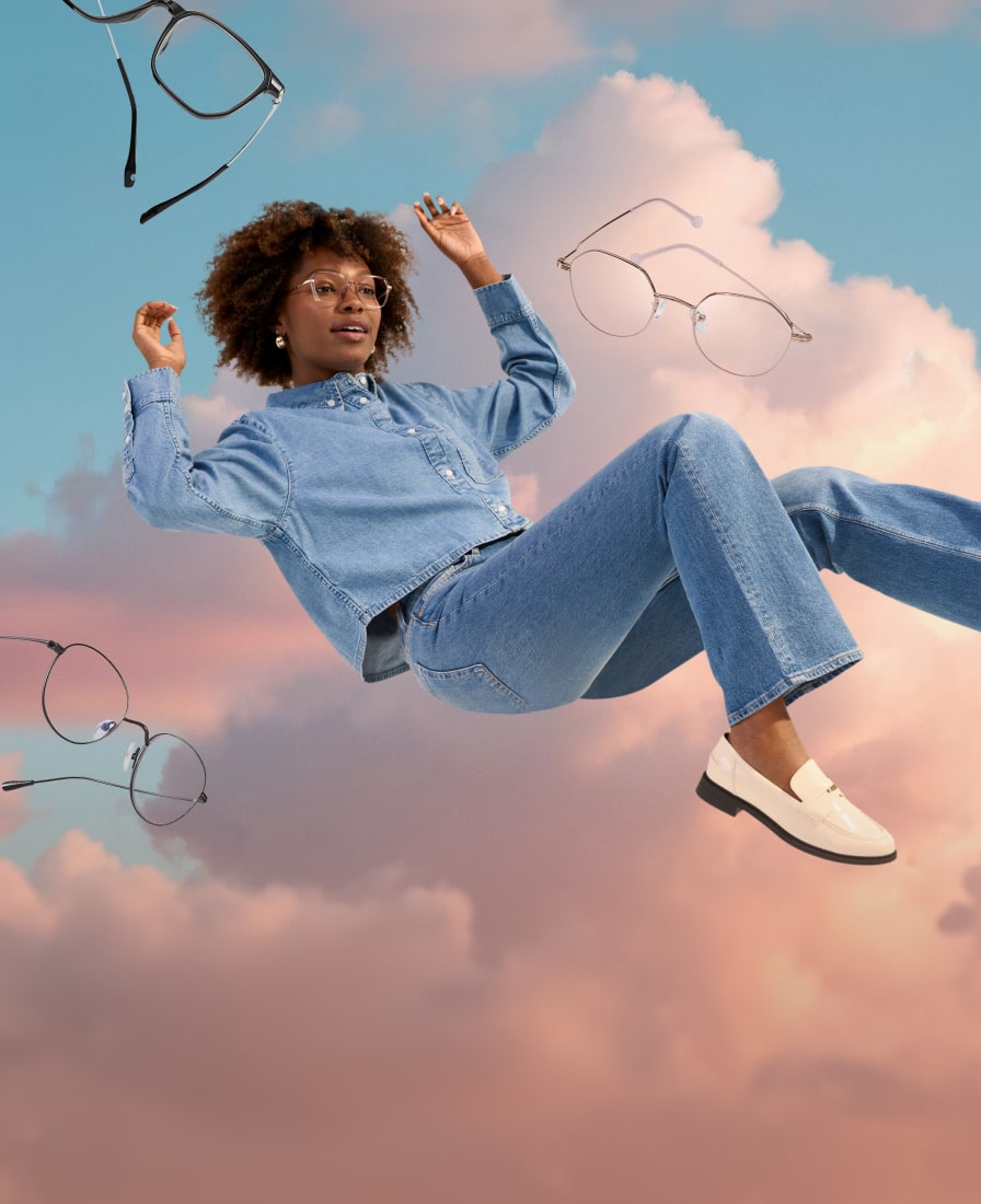 A woman with curly brown hair wearing lightweight geometric glasses, floating in a semi-reclined position in front of a background of pink clouds and blue sky. More pairs of lightweight glasses are floating around her.